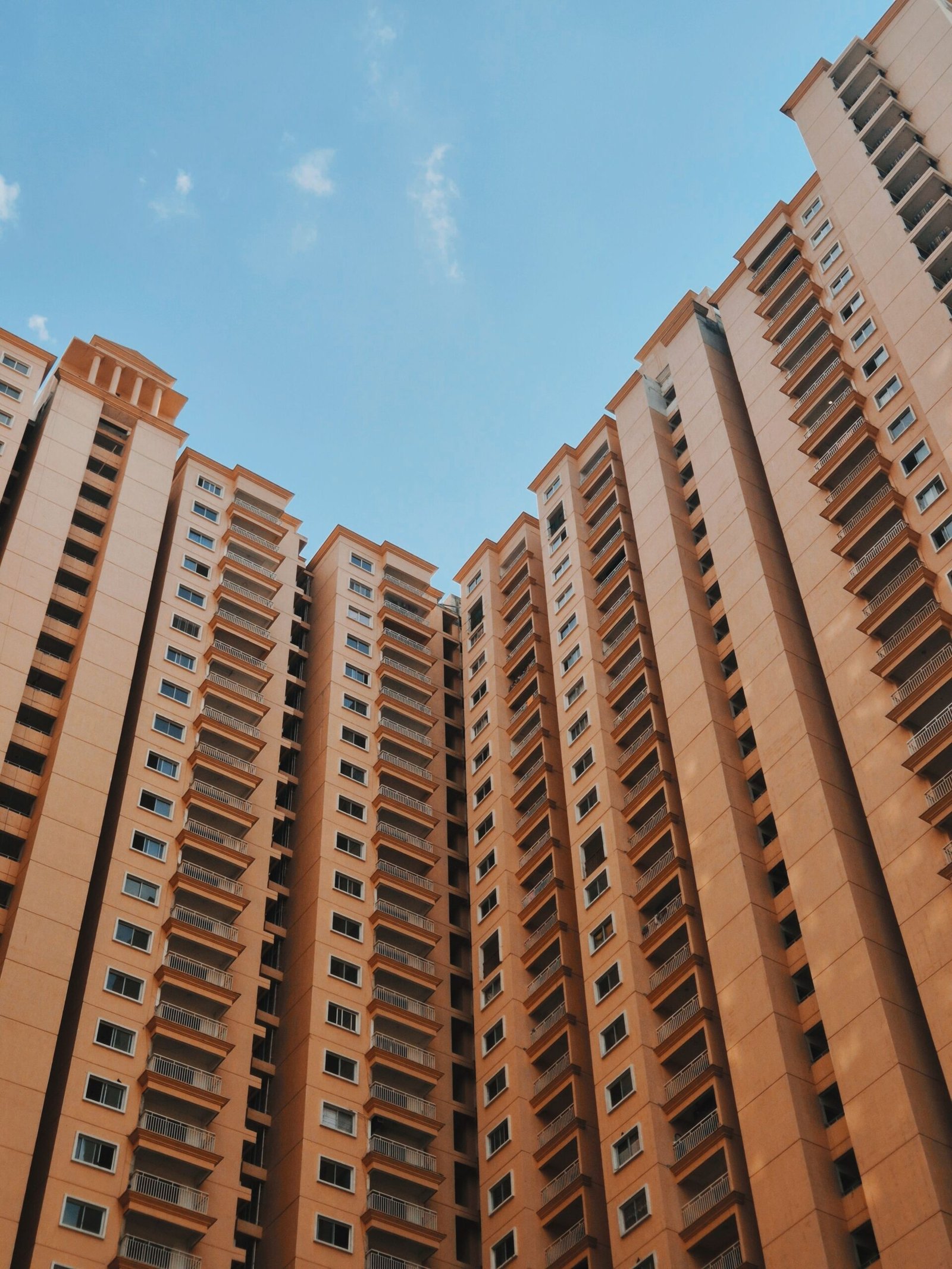 A cluster of modern high-rise apartment buildings reaching into a clear blue sky.